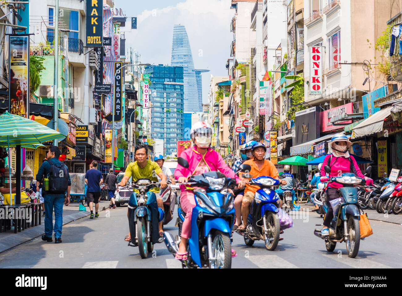 Vue sur Bui Vien Street avec ses panneaux, des hôtels, Tour Bitexco et vietnamiens, porter des vêtements colorés, ride les scooters. Banque D'Images