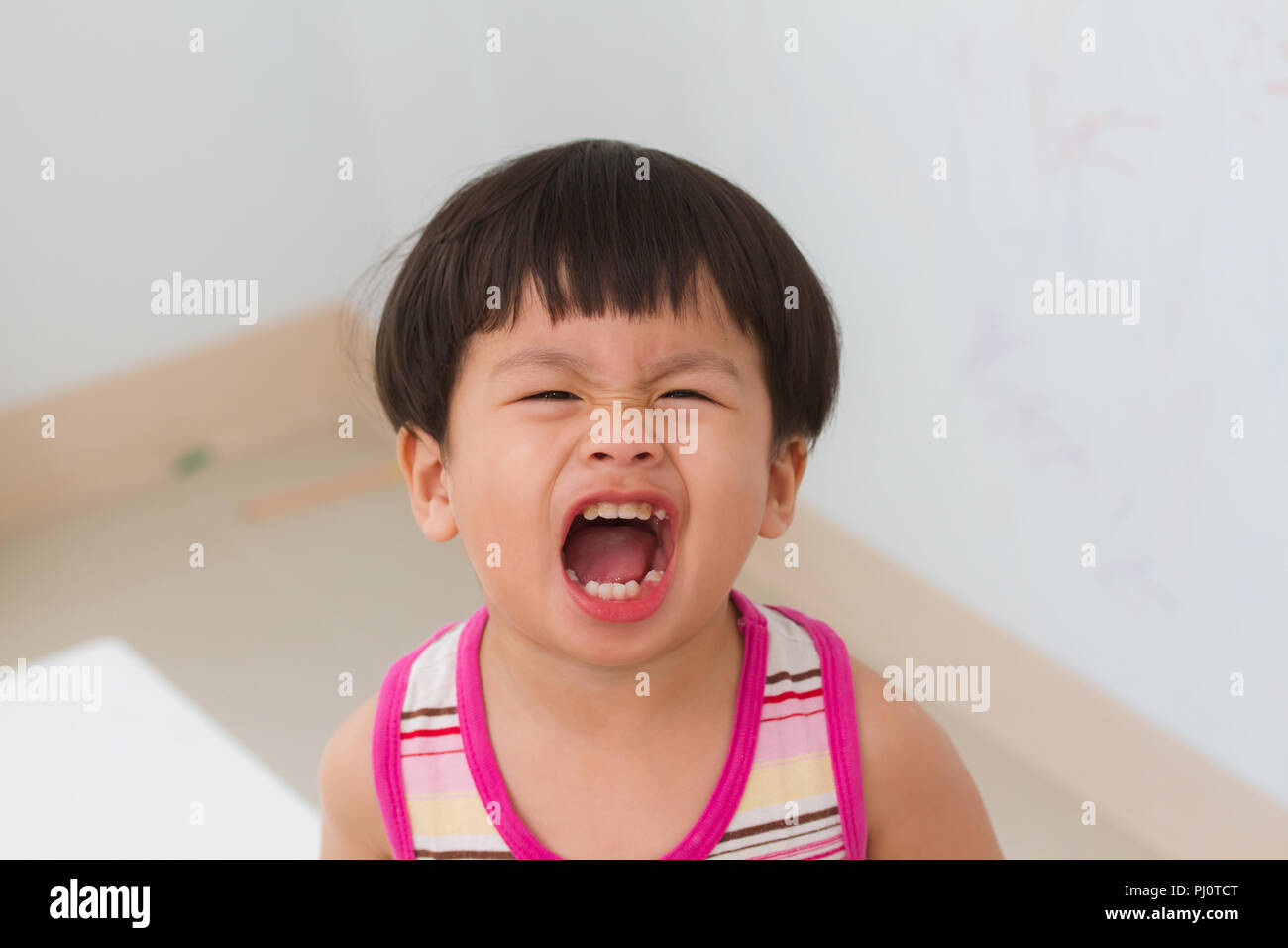 Petit garçon ouvrir la bouche cri sur mur blanc, l'arrière-plan Banque D'Images