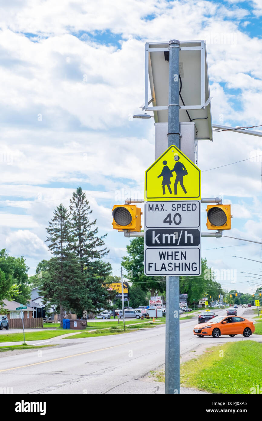 Panneau d'avertissement de vitesse dans les zones scolaires sur une rue animée. Banque D'Images