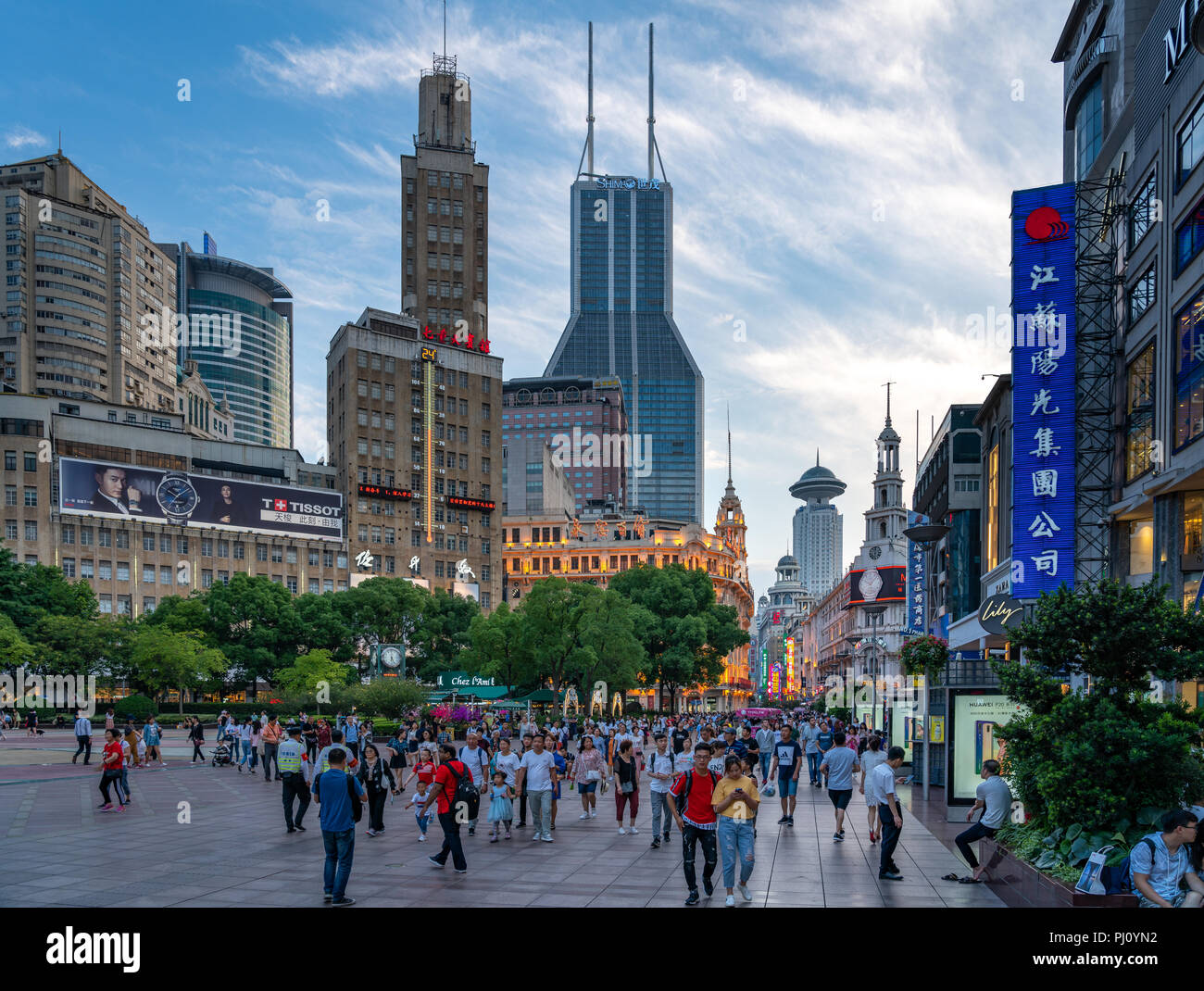 Une foule de promenades à travers la Place du Peuple à Shanghai en Chine, alors que le soleil se couche sur une belle journée d'été. Banque D'Images