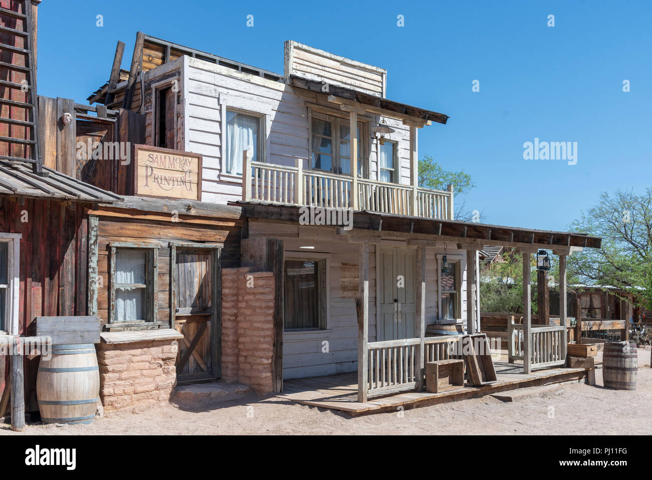 Vieux bois de l'ouest et les bâtiments en briques d'adobe, avec deux étages, véranda en bois, de barils et la saleté street. Signes sur les bâtiments. Banque D'Images
