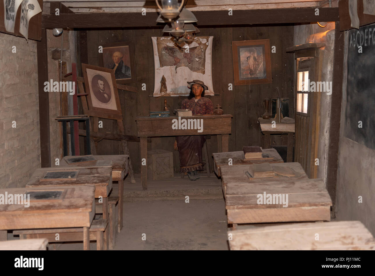 Intérieur de l'ancienne école de l'ouest chambre avec un enseignant, et un bureau en bois dans un bâtiment d'adobe. Banque D'Images