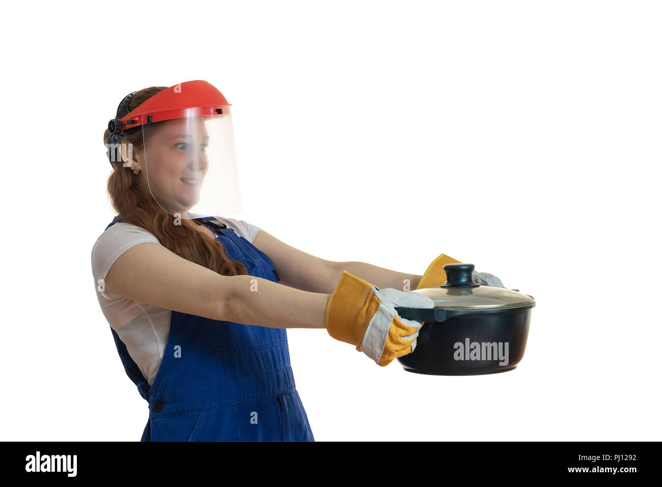 La fille en vêtements de travail et un masque de protection est titulaire d'une casserole à la main, représentant une surprise. Banque D'Images