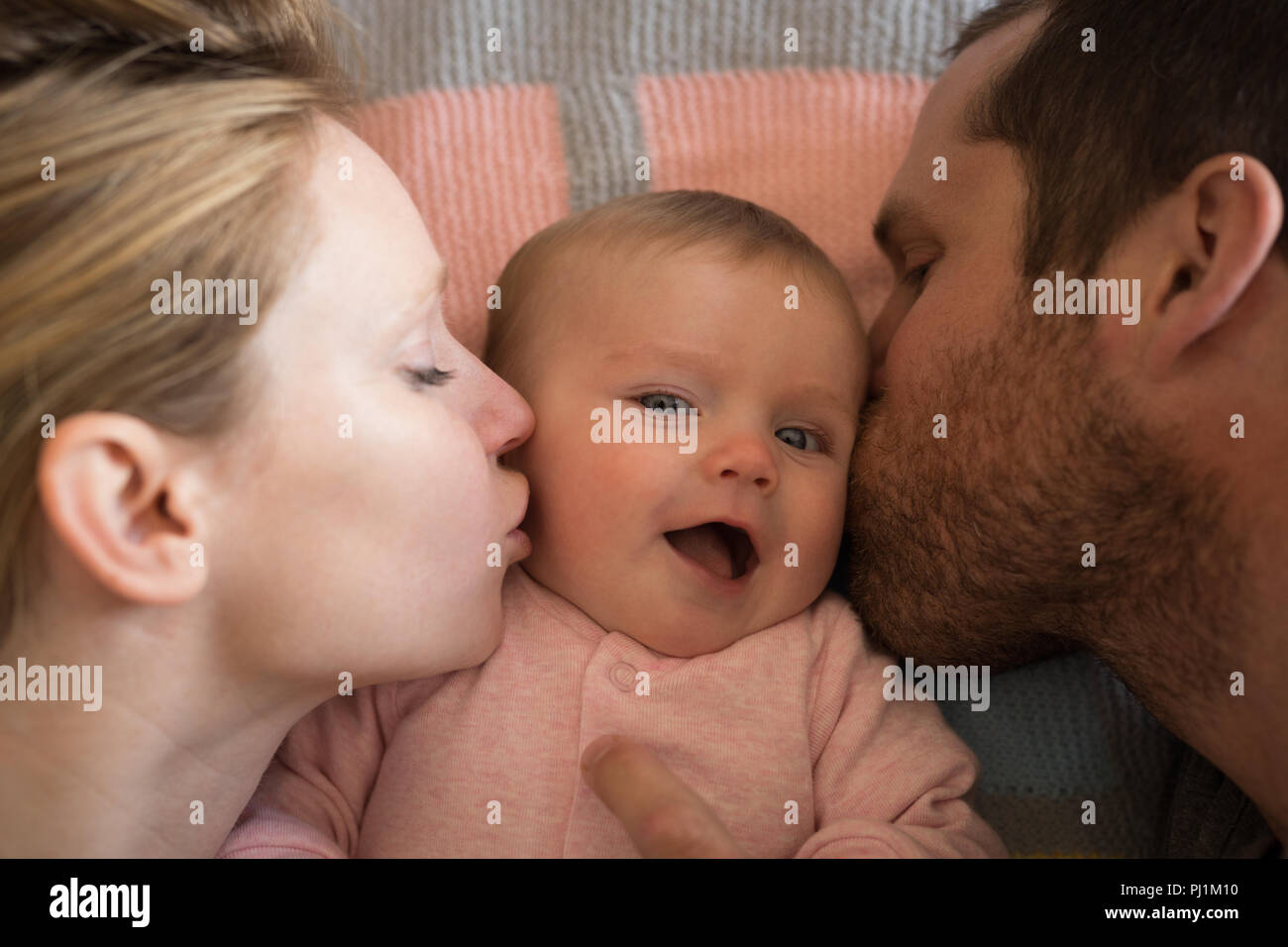 Les parents s'embrasser sur le lit de bébé à la maison Banque D'Images