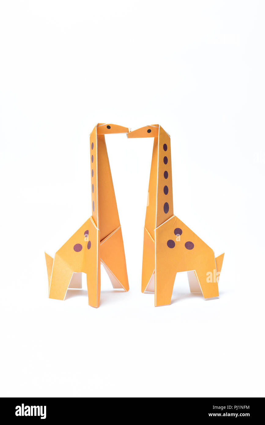 Deux girafes kiss origami jaune sur fond blanc Banque D'Images