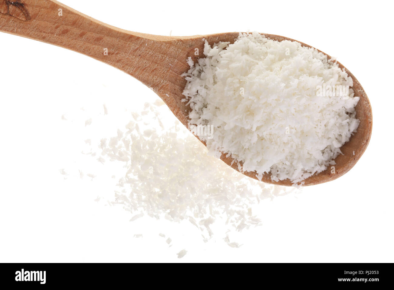 Tas de flocons de noix de coco en cuillère en bois isolé sur fond blanc. Banque D'Images