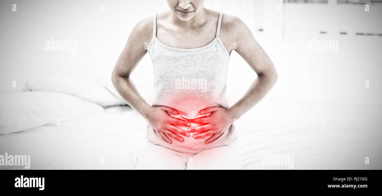 Image composite de femme avec douleur à l'estomac sitting in bed Banque D'Images