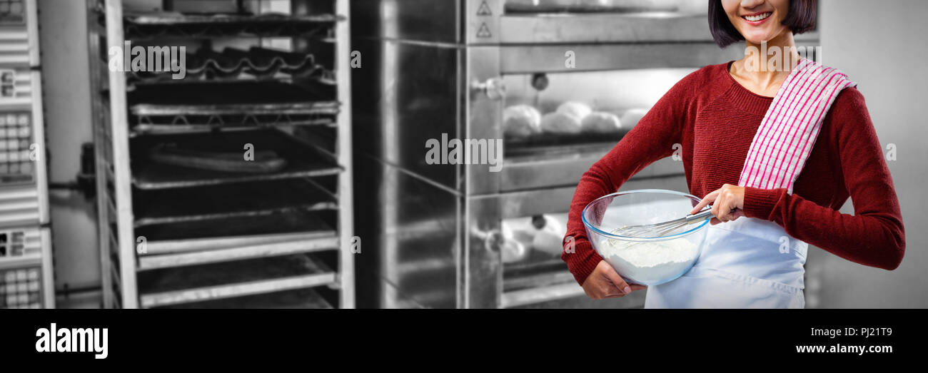 Portrait of female chef de mélanger la farine dans un bol avec un fouet Banque D'Images