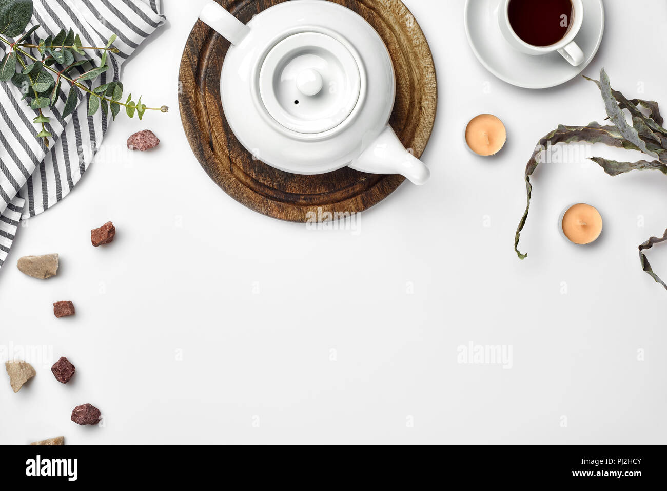 Une théière en porcelaine blanche sur une planche en bois et une tasse blanche avec plateau sur une table. Vue d'en haut. Copier l'espace. Banque D'Images