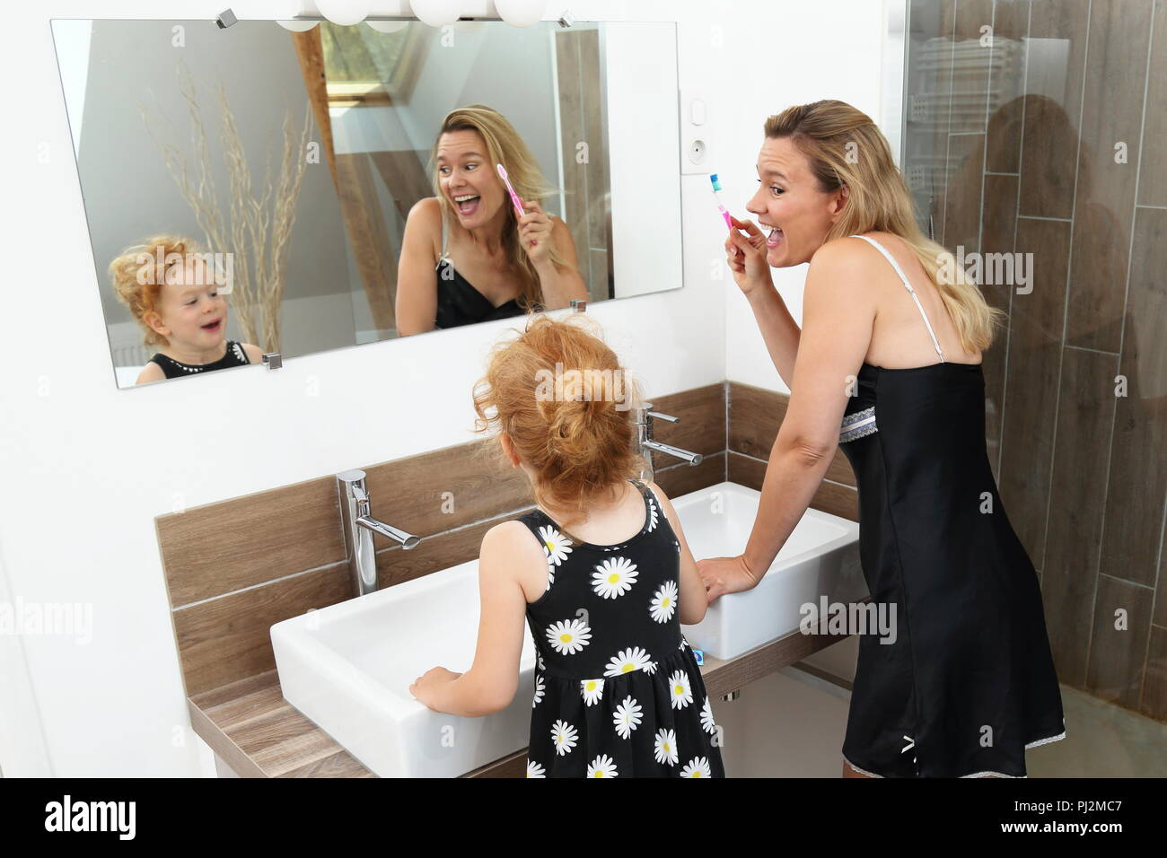 Mère et fille s'amuser pendant le brossage de dents dans une salle de bains moderne Banque D'Images