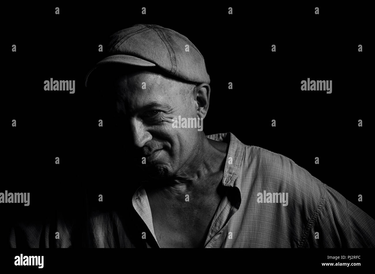 Portrait d'un homme âgé dans un bouchon sur un fond sombre . Banque D'Images