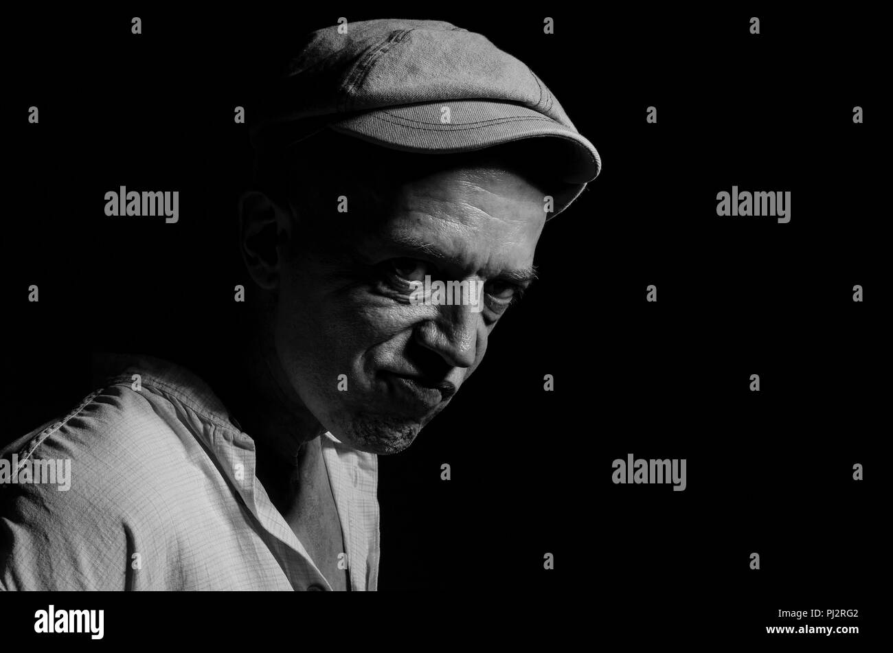 Portrait d'un homme âgé dans un bouchon sur un fond sombre . Banque D'Images