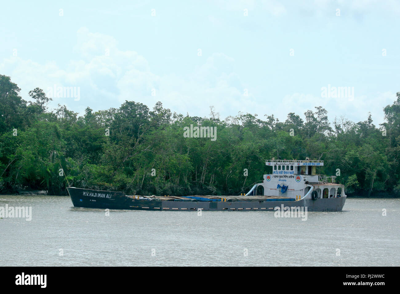 Un cargo naviguant près de la banque d'une rivière à l'intérieur les Sundarbans en dépit des risques écologiques. Bagerbat, Bangladesh Banque D'Images