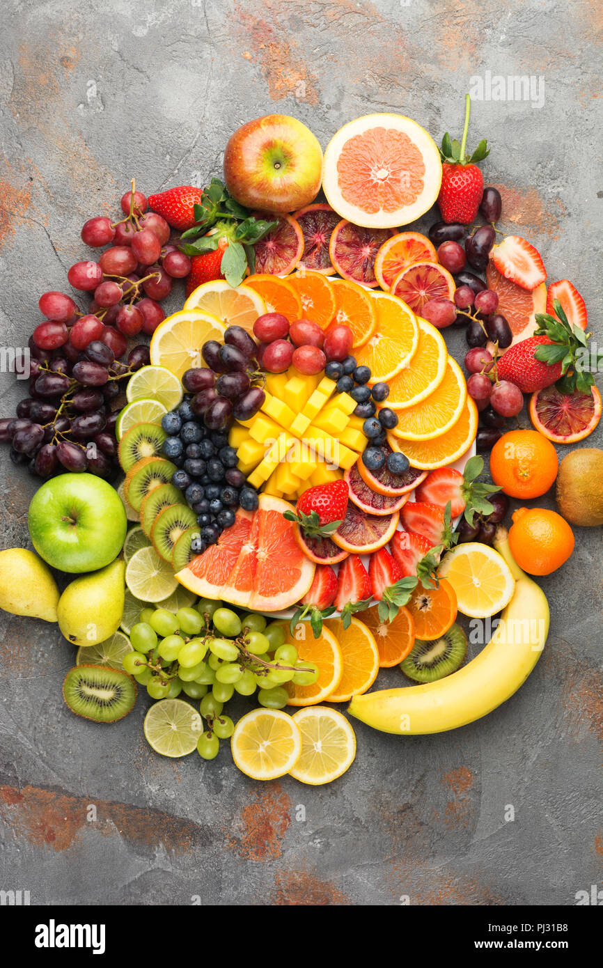 Les fruits sains en arrière-plan des couleurs arc-en-ciel oranges pommes poires raisins fraises kiwis mangues sur la table de béton gris, vue du dessus, copiez l'espace, selective focus Banque D'Images