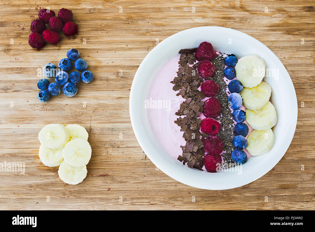 Un Smoothie bol avec les baies fraîches, banane, amandes et noix et chocolat pour un petit-déjeuner végétarien et végétalien Banque D'Images