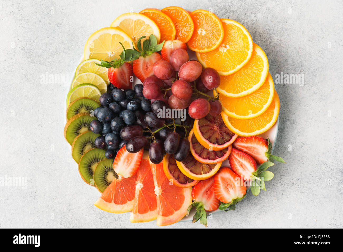 Fruits et baies sains en couleurs arc-en-plateau, fraises, bleuets, raisins, kiwis, pamplemousse, pamplemousse sur tableau blanc, vue du dessus, copiez l'espace pour texte, selective focus Banque D'Images