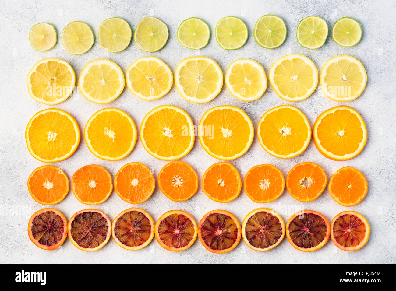 Les agrumes riches en vitamine C, les oranges, citrons, limes, les satsumas disposés dans les lignes. Vue de dessus, l'arrière-plan coloré Banque D'Images