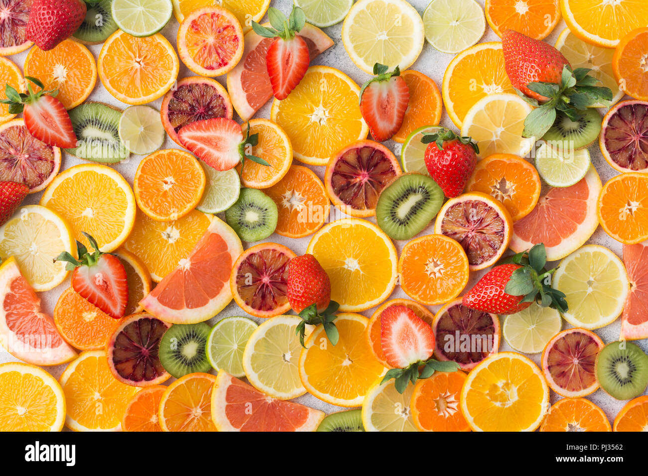 Modèle des fruits colorés, les oranges, les clémentines, les oranges, kiwis, fraises et pamplemousses sur tableau blanc arrière-plan, Vue de dessus, selective focus Banque D'Images