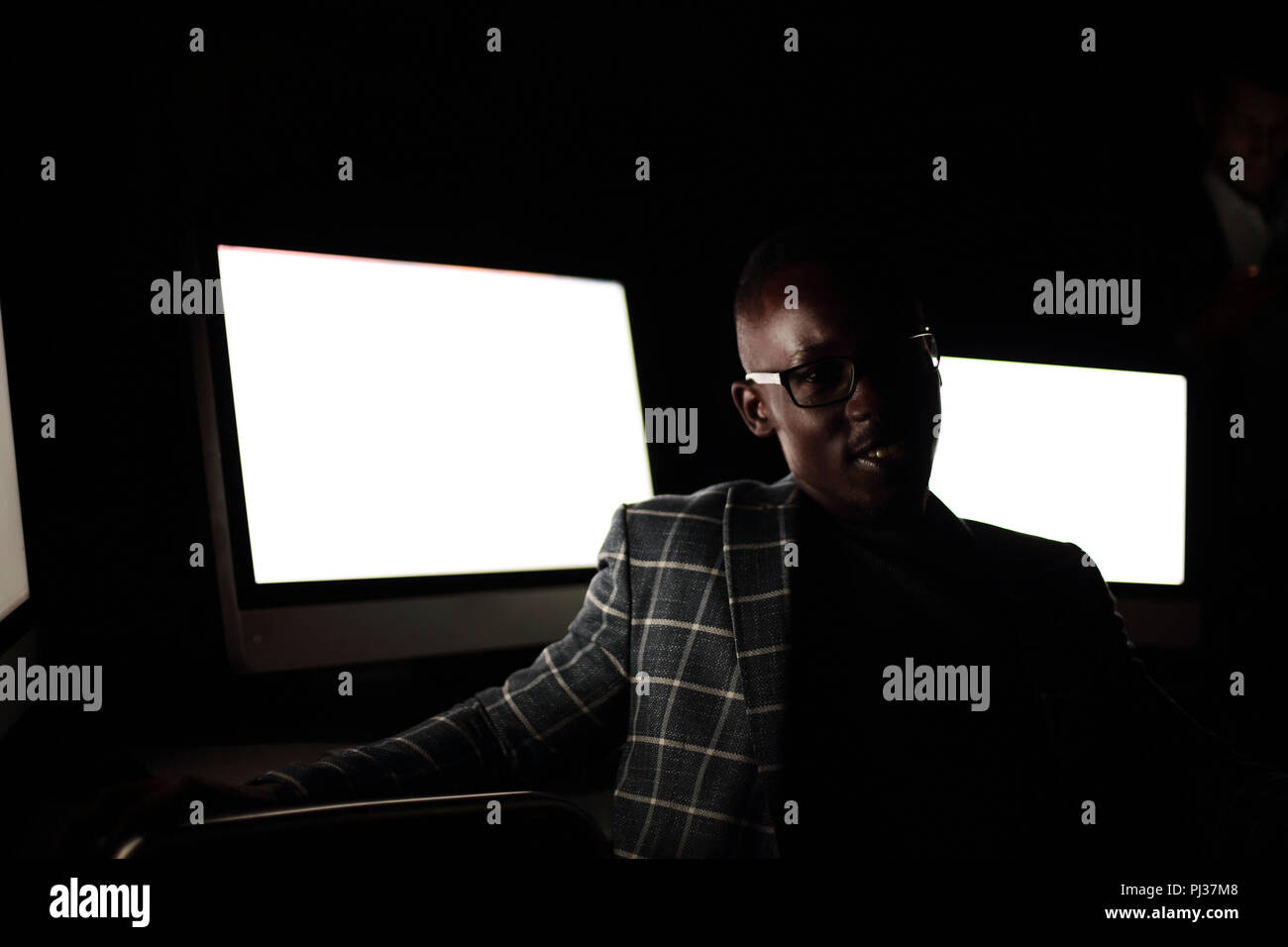 Young businessman sitting in computer room at night Banque D'Images