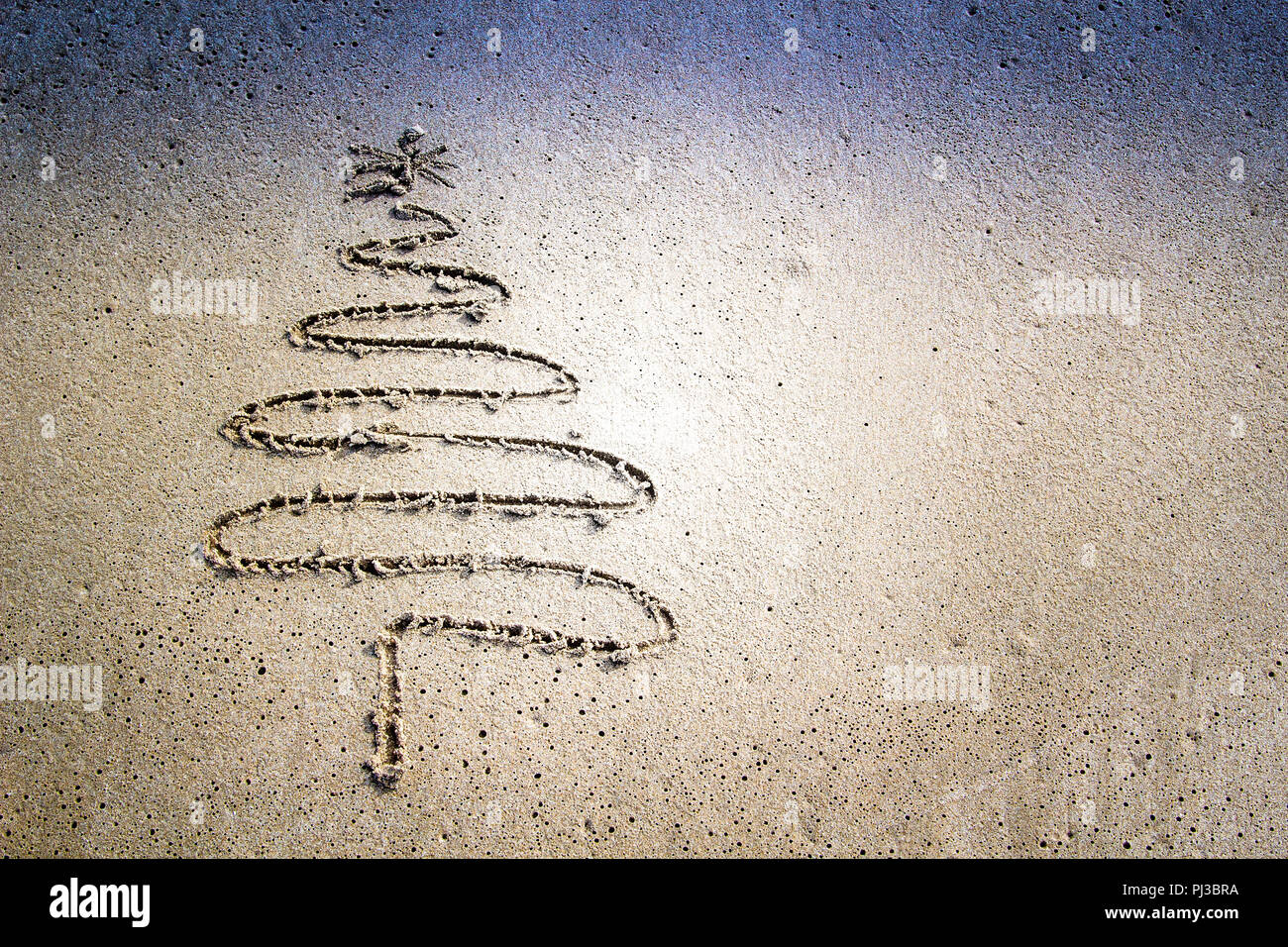 Arbre de Noël dessiné dans le sable à la plage. Banque D'Images