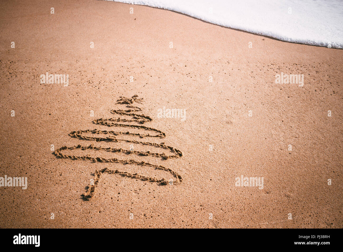 Arbre de Noël dessiné dans le sable à la plage. Banque D'Images