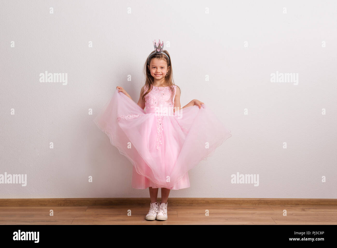 Petite fille princesse heureuse avec bandeau de la couronne en studio sur un fond blanc. Banque D'Images