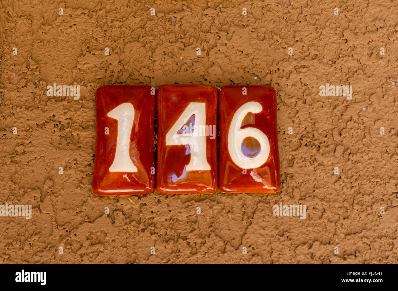 Le nombre 146 sur un mur en stuc brun. Chiffres blancs sur l'orange de carreaux en céramique. Banque D'Images