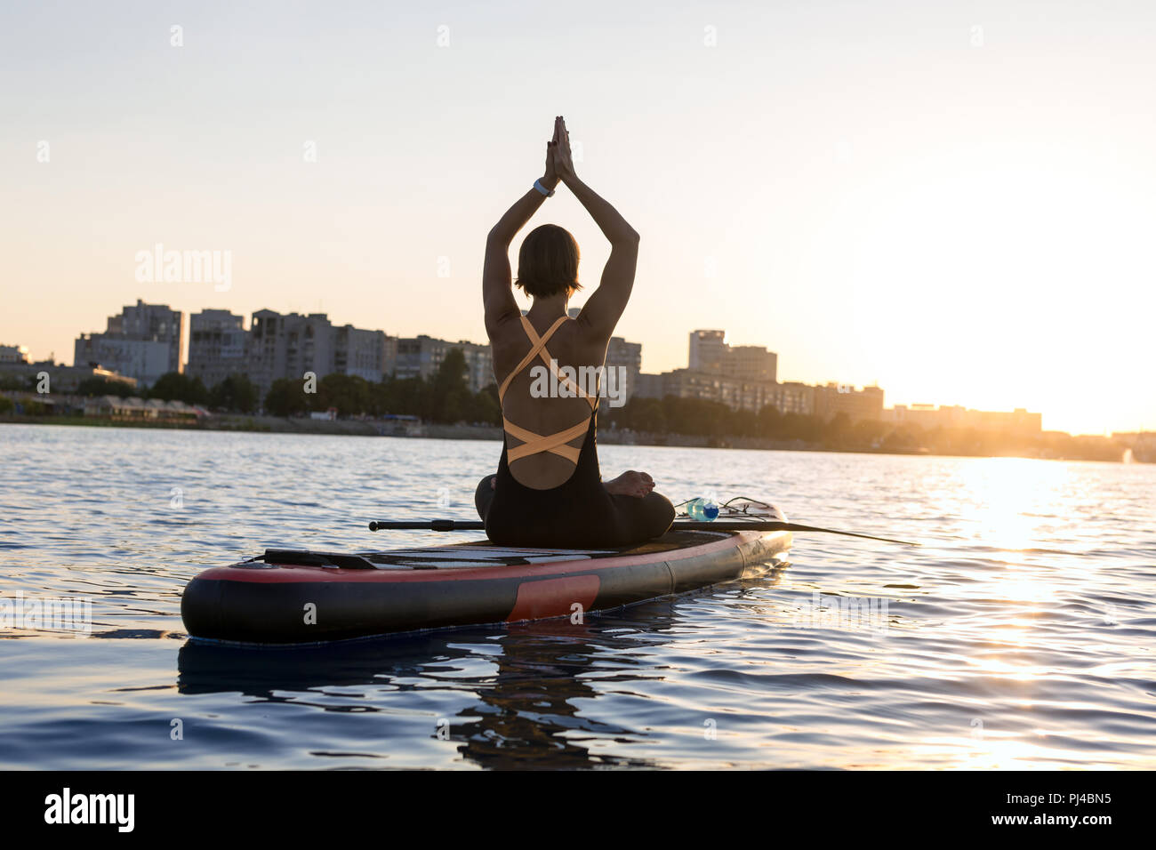 Silhouette d'une jeune fille svelte engagés dans le yoga sur un arrière-plan de la ville Banque D'Images