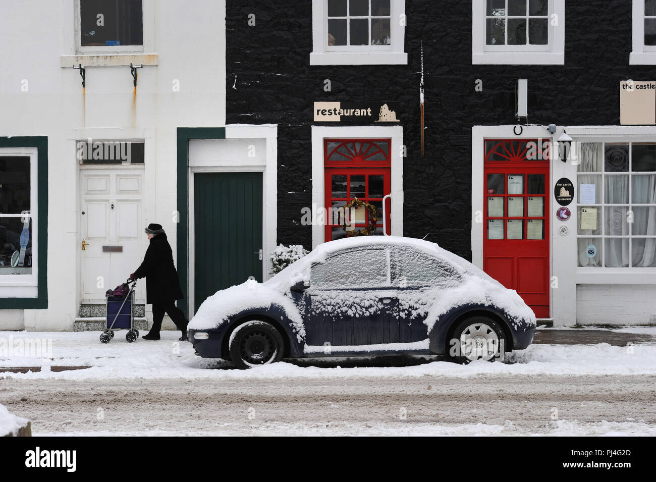 En passant devant les maisons colorées dans la neige de l'hiver dans la région de Castle Street, Kirkcudbright, Dumfries and Galloway Banque D'Images