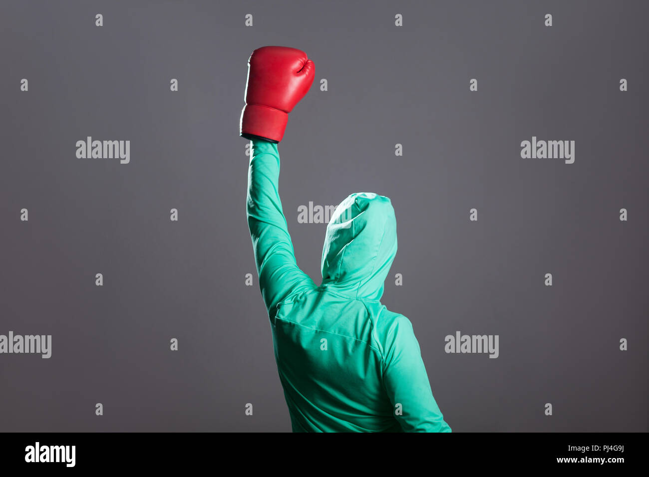 Vue de côté arrière du boxer femme musulmane gagnant en vert sport islamique, debout en rouge des gants de boxe et de célébrer sa victoire, mains en l'intérieur. Banque D'Images