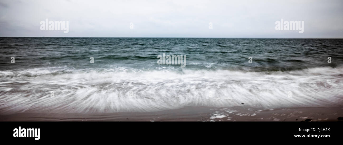 Aller de l'arrière-plan flou artistique de l'écume des vagues qui sont déversés sur la plage Banque D'Images