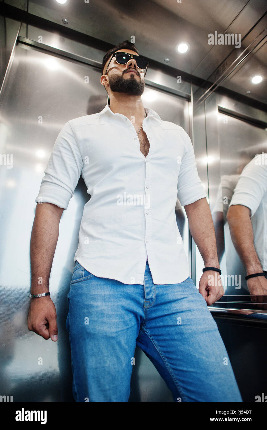 Grand modèle élégant homme arabe en chemise blanche, jeans et lunettes  posées à l'intérieur de l'élévateur Photo Stock - Alamy