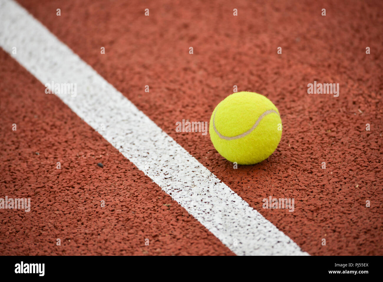Tennis : balle jaune et ligne blanche sur un fond ocre, semblable à l'argile Banque D'Images