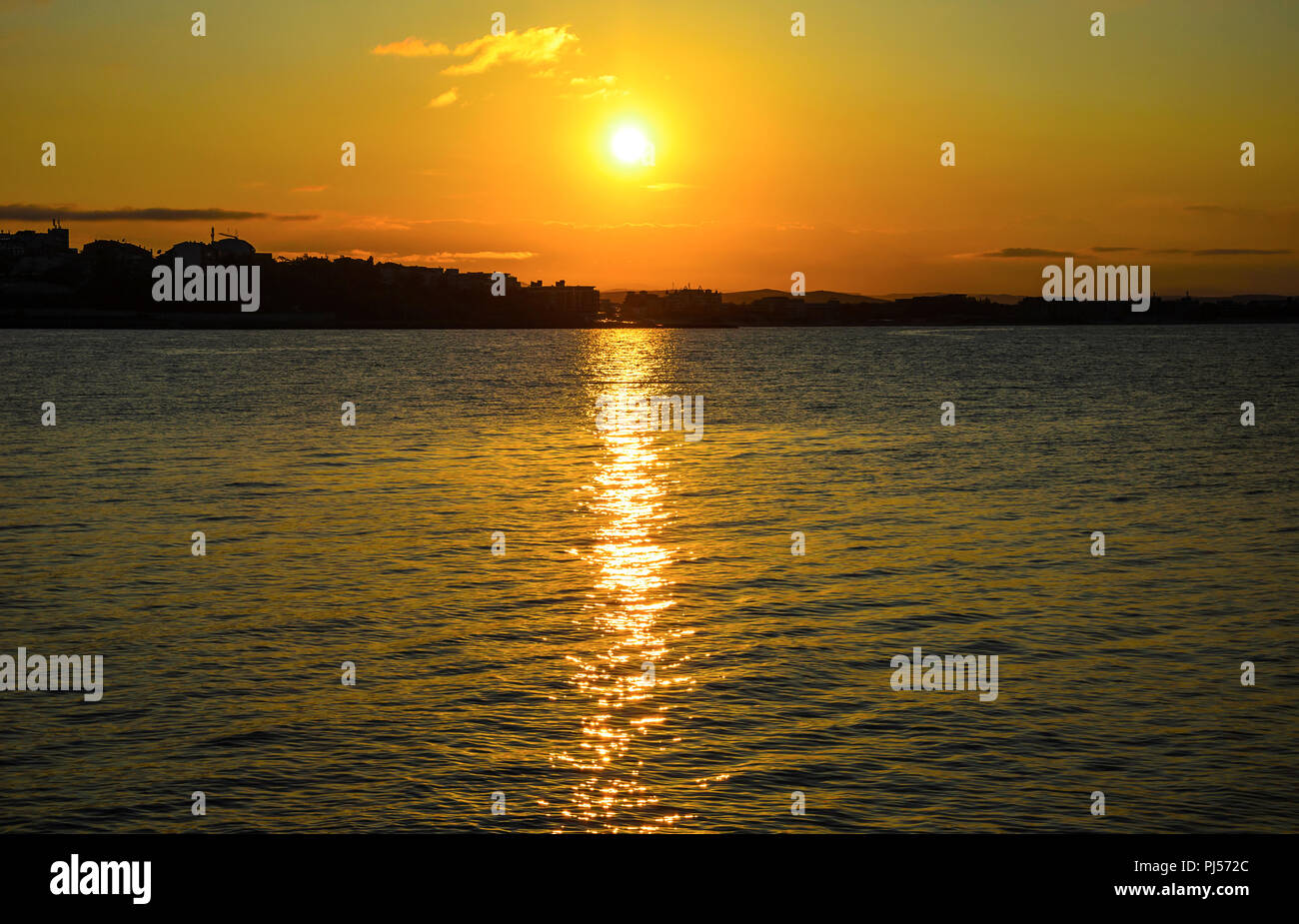 Coucher du soleil sur la côte. Sur l'horizon vous pouvez voir les contours de la ville. Banque D'Images