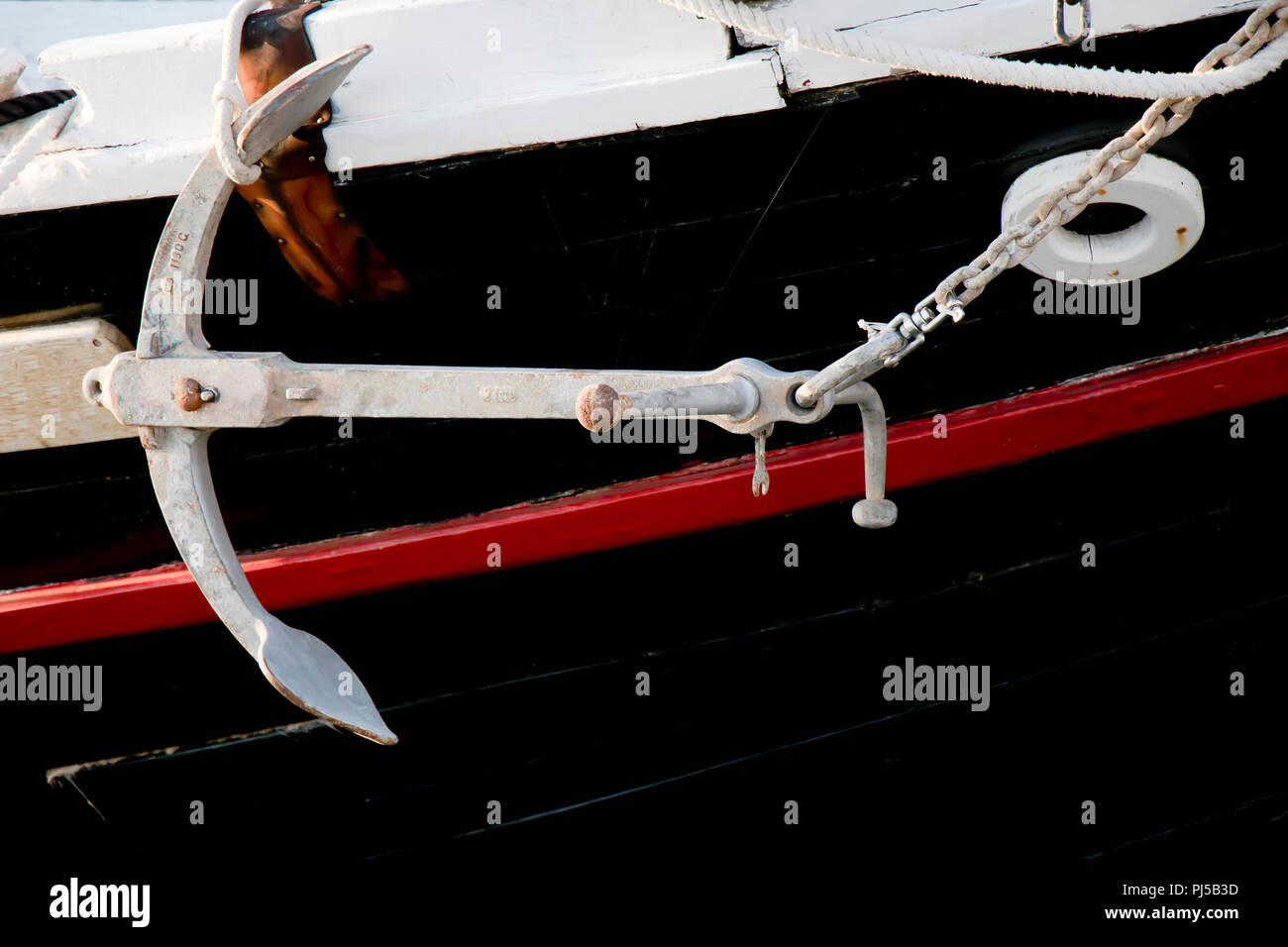 L'ancre attachée au côté d'un noir et blanc rouge , bateau en bois rétro Banque D'Images