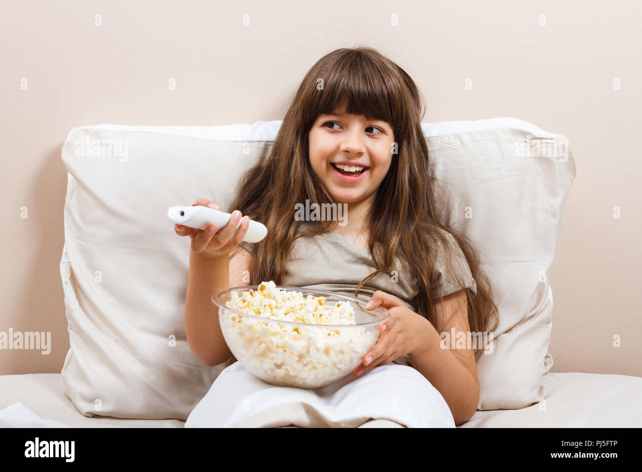 Petite fille est de regarder la télévision et manger du pop-corn dans son  lit Photo Stock - Alamy