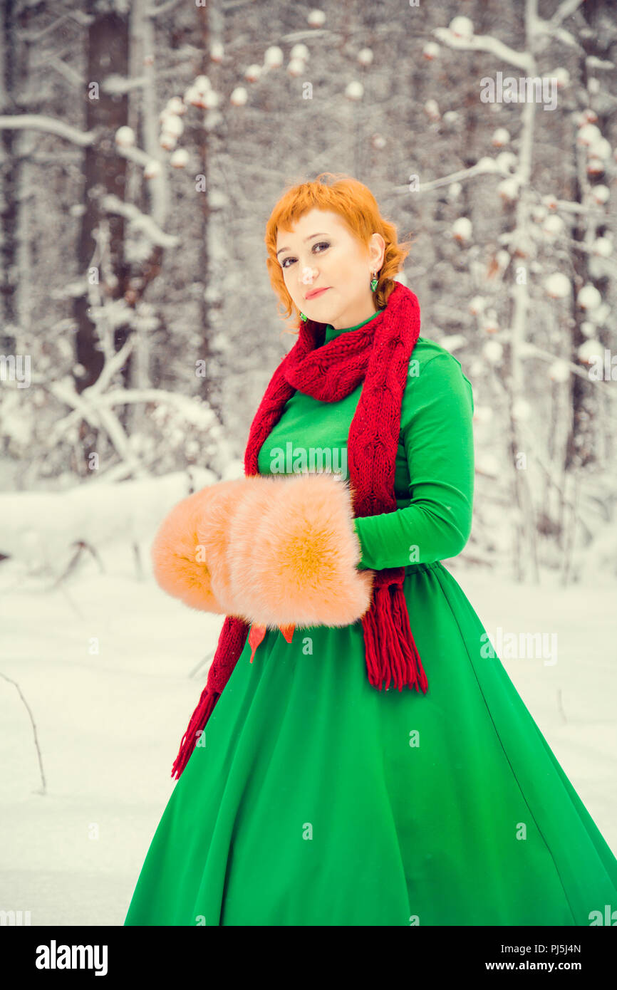 Fiery red-haired woman dans un bal robe vert avec une ceinture en cuir  rouge en costume de Père Noël assistant nain dans la forêt d'hiver avec  d'énormes cand Photo Stock - Alamy