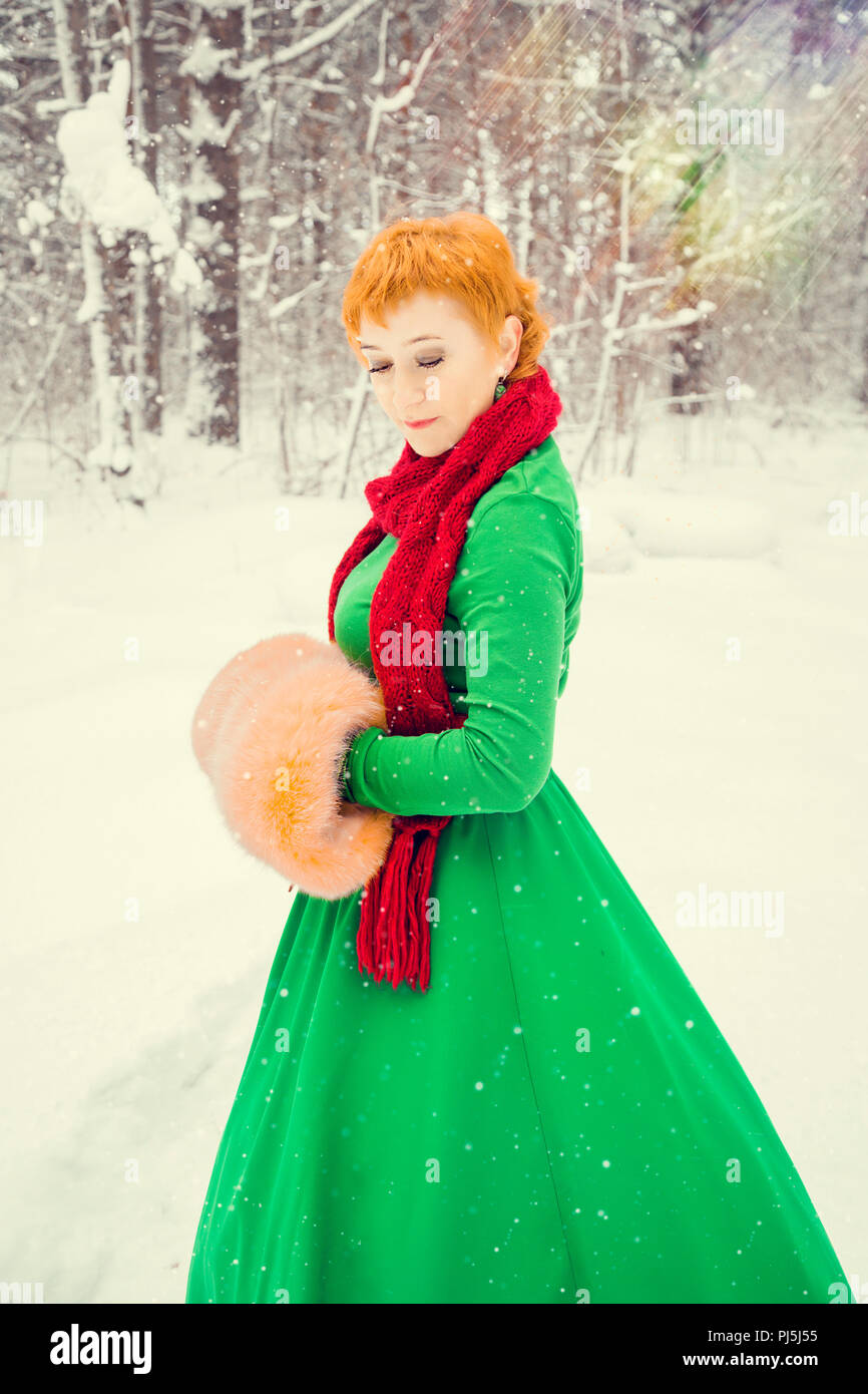 Fiery red-haired woman dans un bal robe vert avec une ceinture en cuir  rouge en costume de Père Noël assistant nain dans la forêt d'hiver avec  d'énormes cand Photo Stock - Alamy