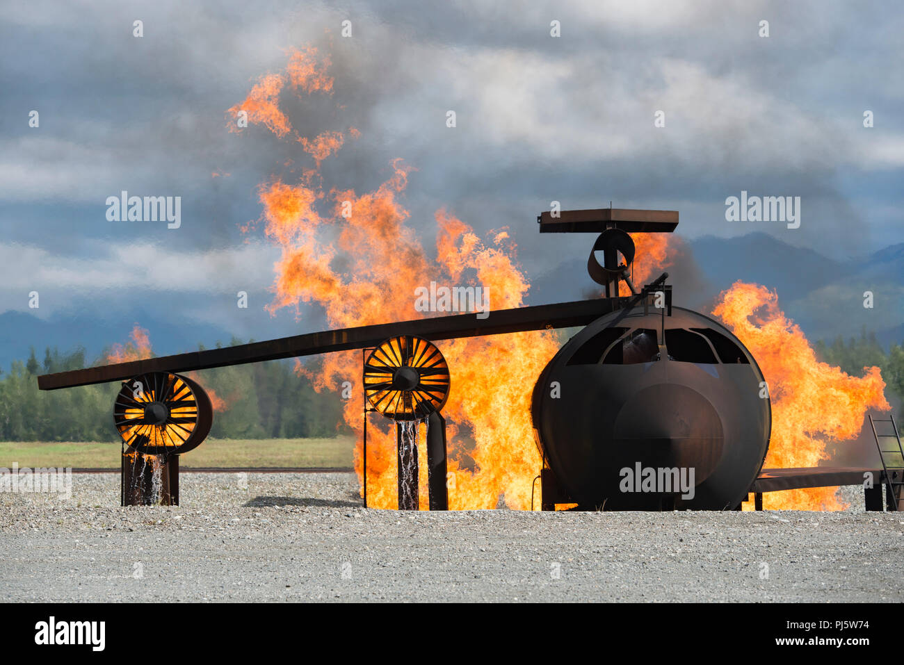 Un simulateur d'incendie de l'avion est la proie des flammes pour les forces aériennes américaines des spécialistes de la protection incendie, non représentée, affecté à la 673e Escadron d'Ingénieur Civil, dans leur conduite à l'état de préparation de guerre l'incendie formation at Joint Base Elmendorf-Richardson, Alaska, le 24 août, 2018. Au cours de la formation de préparation à l'Armée de l'air les pompiers ont enfilé divers niveaux de protection axé sur la mission de posture (MOPP) et pratiqué répondant aux situations d'urgence à une simulation d'environnement toxique lors d'un incident chimique, biologique, radiologique ou nucléaire grève. (U.S. Air Force photo par Alejandro Peña) Banque D'Images
