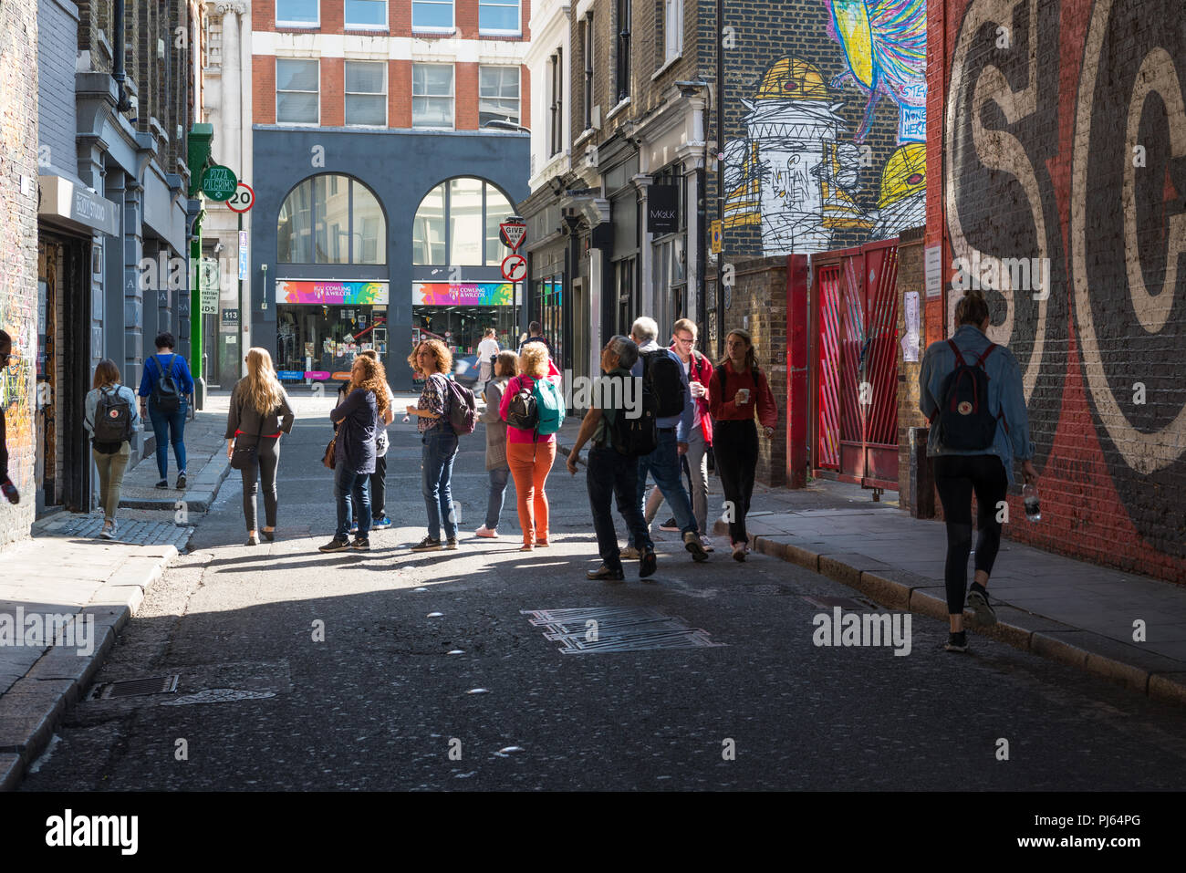 Personnes regardant l'art de mur rideau en route, Hoxton, Shoreditch, London, England, UK Banque D'Images