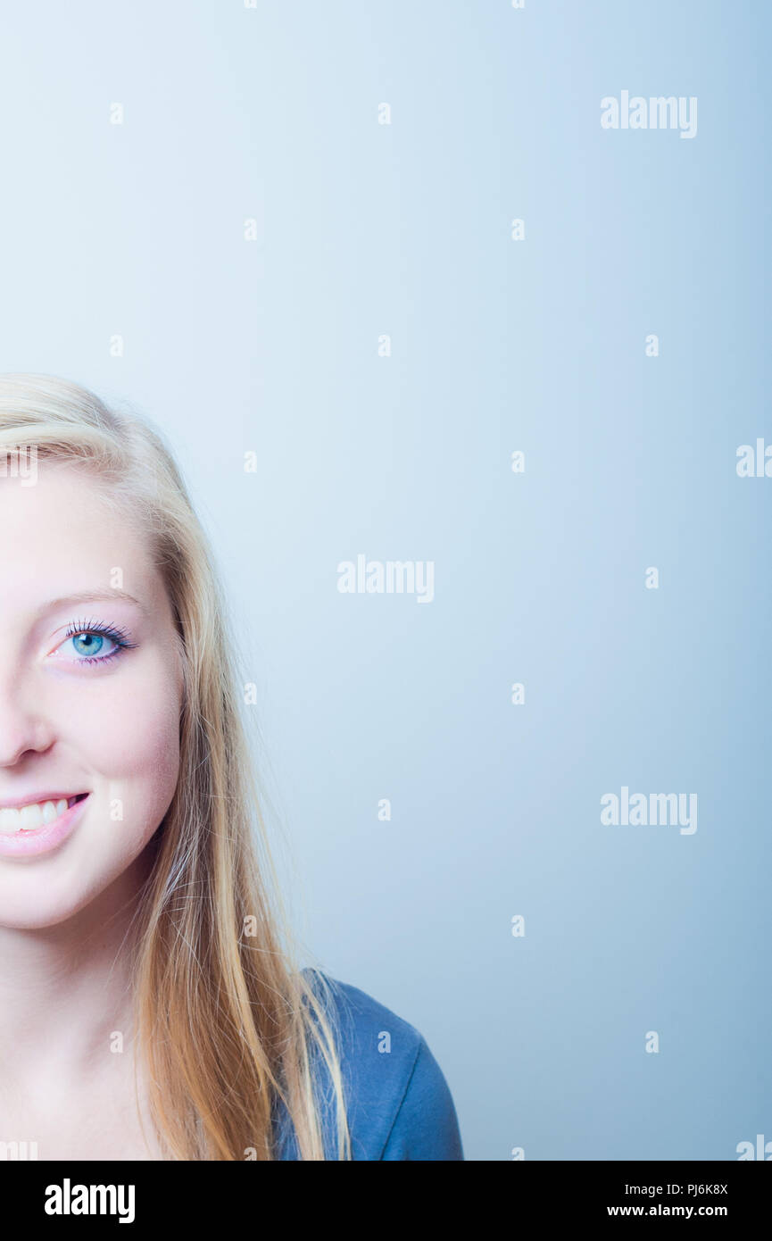 Jeune femme blonde aux yeux bleus, souriant, moitié face portrait Banque D'Images