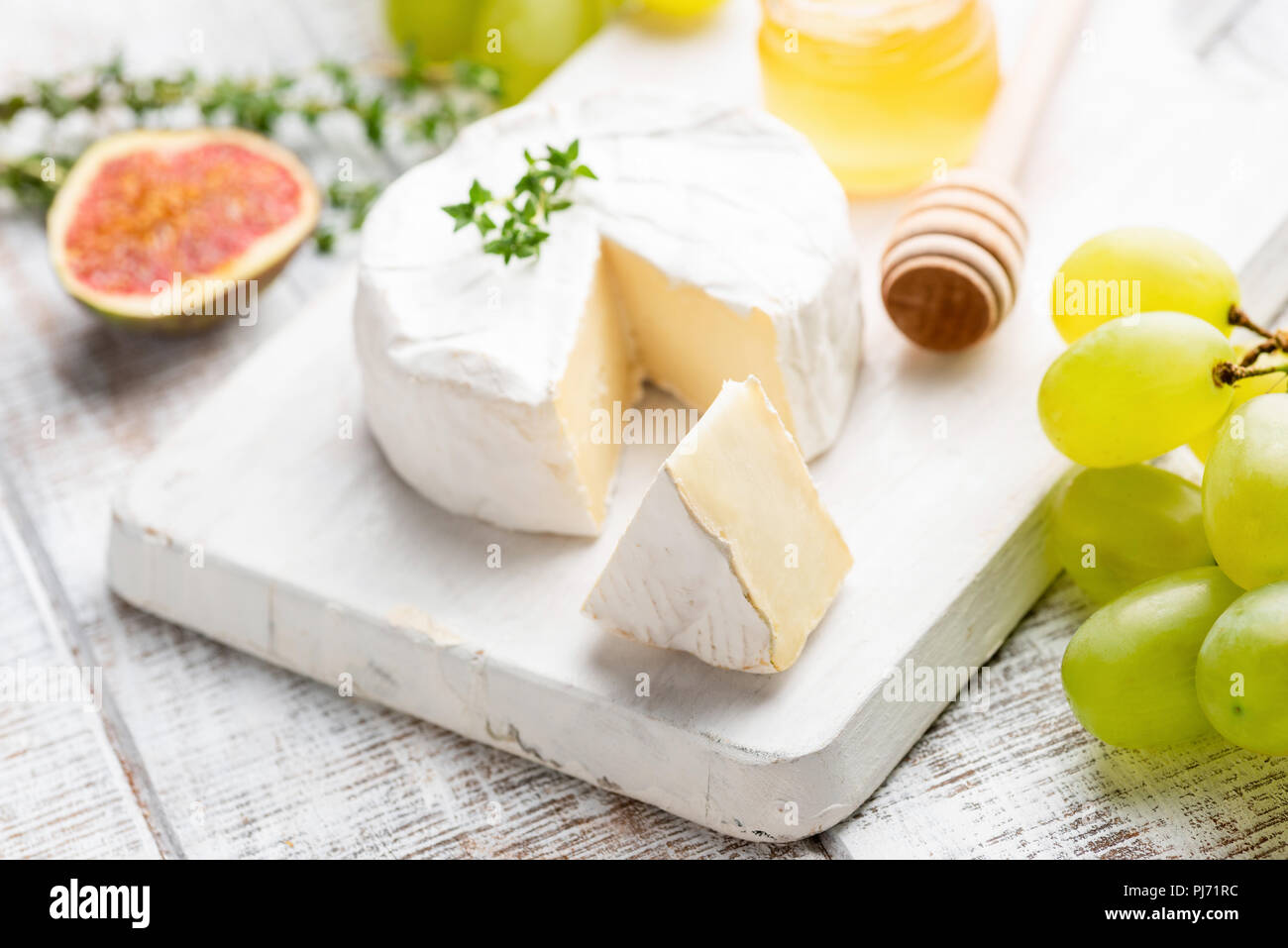 Le Camembert ou le brie avec raisins, figues et miel sur blanche en bois servant de sélection. Vue rapprochée, selective focus Banque D'Images