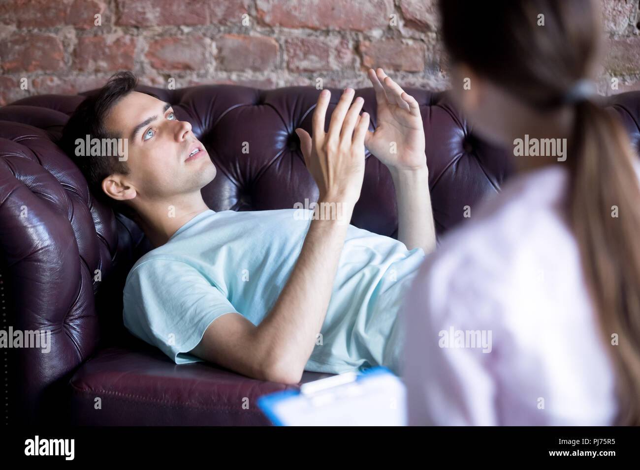 Homme étendu et de parler avec la femme, à la psychothérapeute Banque D'Images