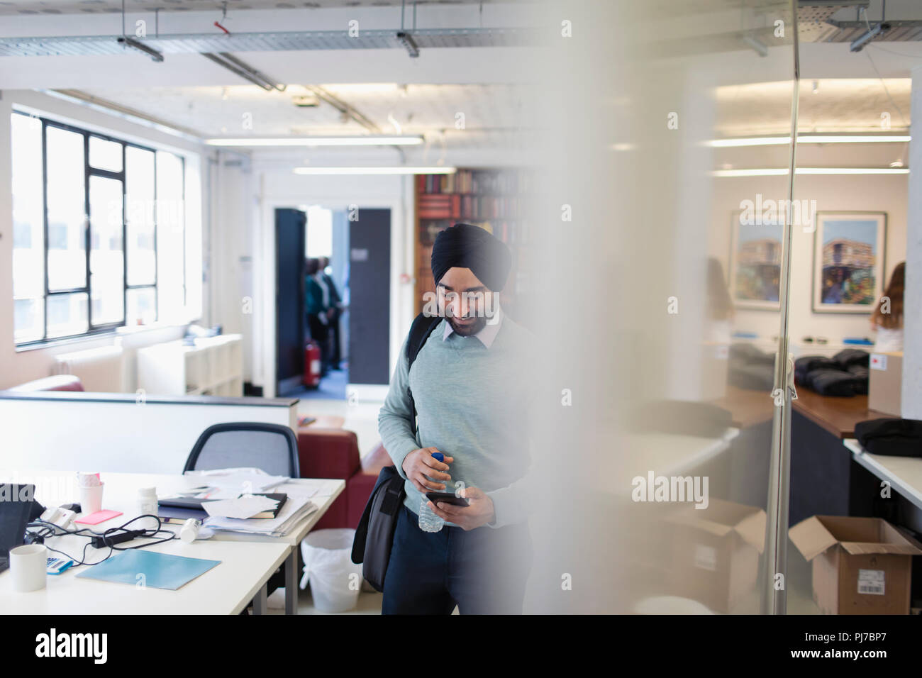 Homme d'affaires indien en turban avec smart phone in office Banque D'Images