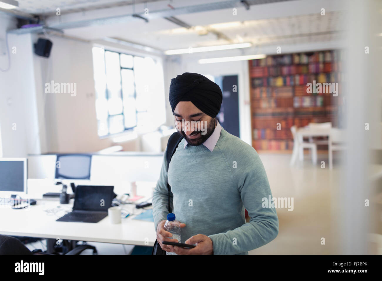 Homme d'affaires indien en turban avec smart phone in office Banque D'Images