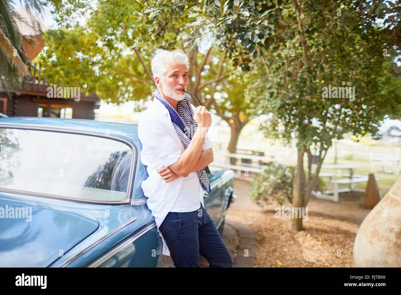 Portrait homme confiant biting pointe de voiture à lunettes Banque D'Images