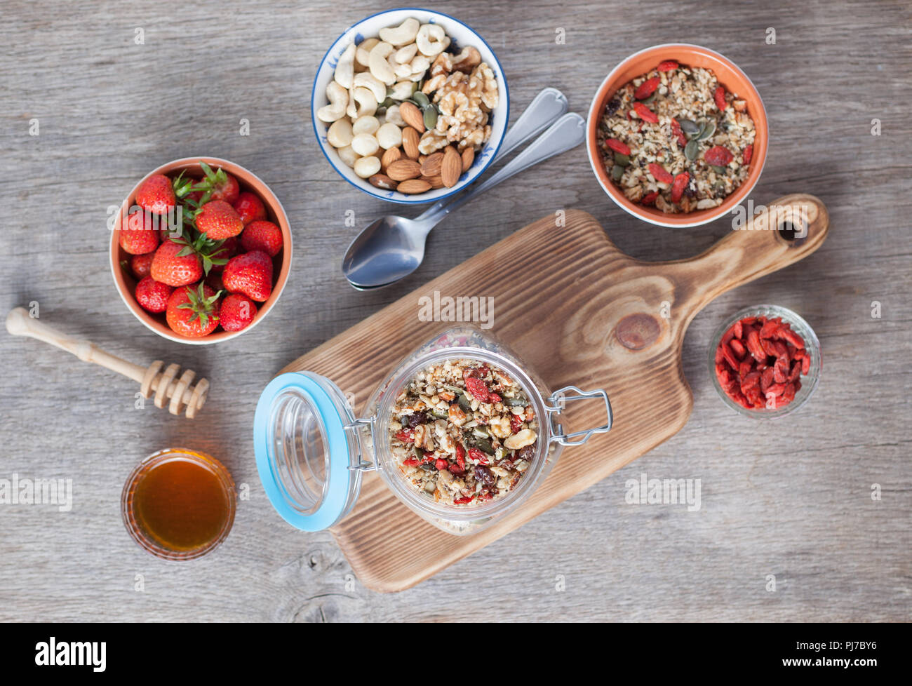 L'avoine de céréales muesli, paléo-aliments crus : les noix, les graines, les baies de goji, Chia, du miel et des fraises, selective focus sur le muesli dans la mason Banque D'Images
