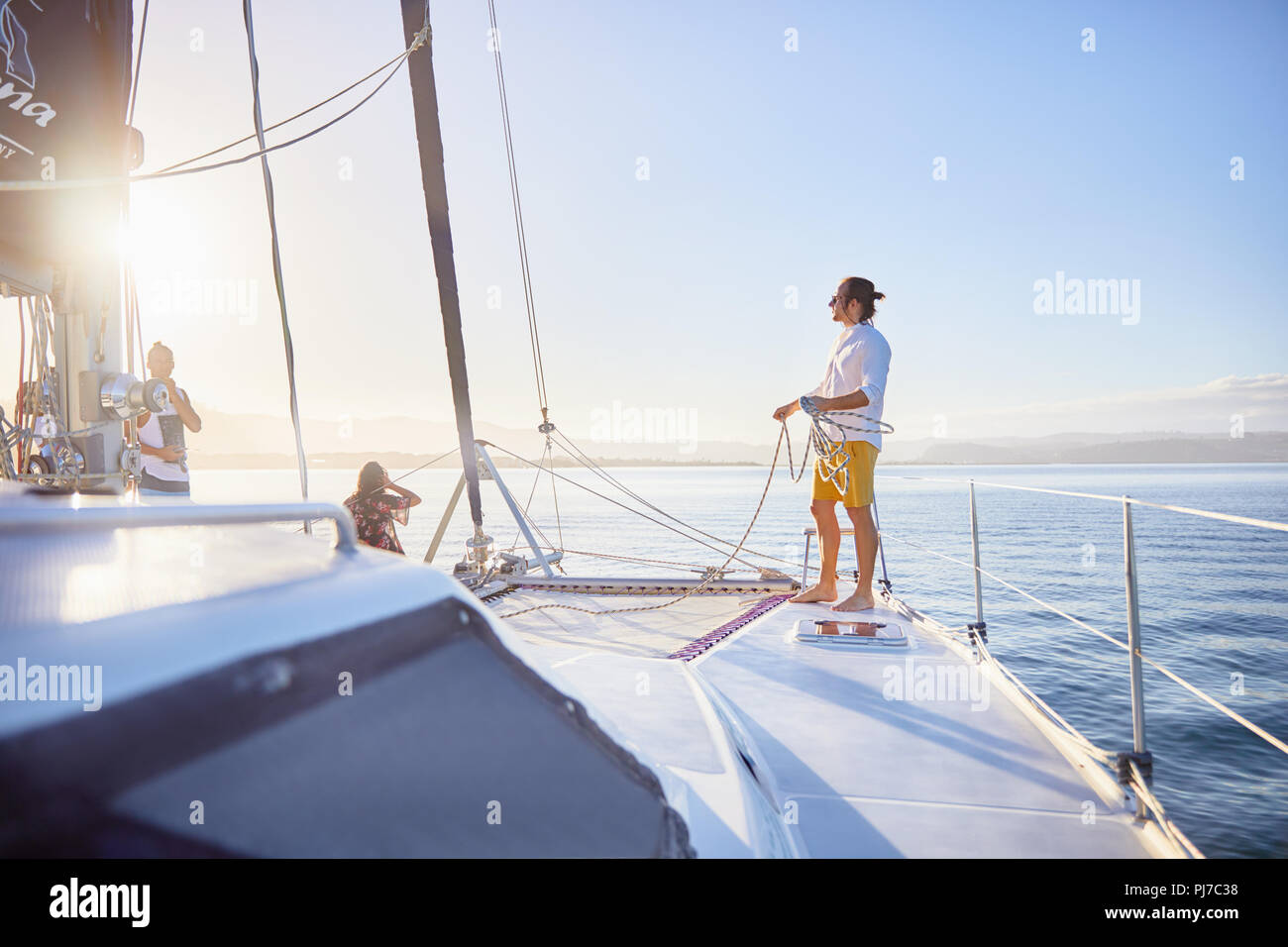 Jeune homme tenant la corde de gréement sur catamaran ensoleillée Banque D'Images