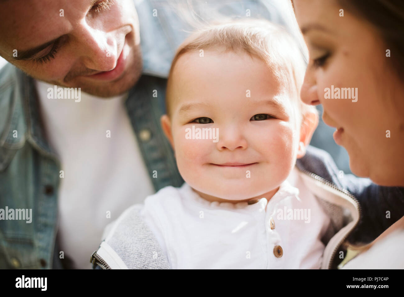 Les parents holding baby boy looking at camera Banque D'Images