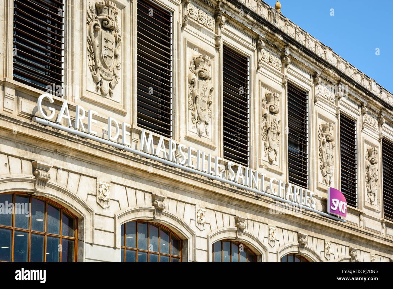 La façade de la gare Saint-Charles à Marseille, France, avec le nom de la station et le logo de la SNCF dans le cadre de l'Armoiries des villes desservies. Banque D'Images